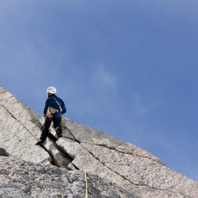 Me climbing on granite cracks between deep snow patches  